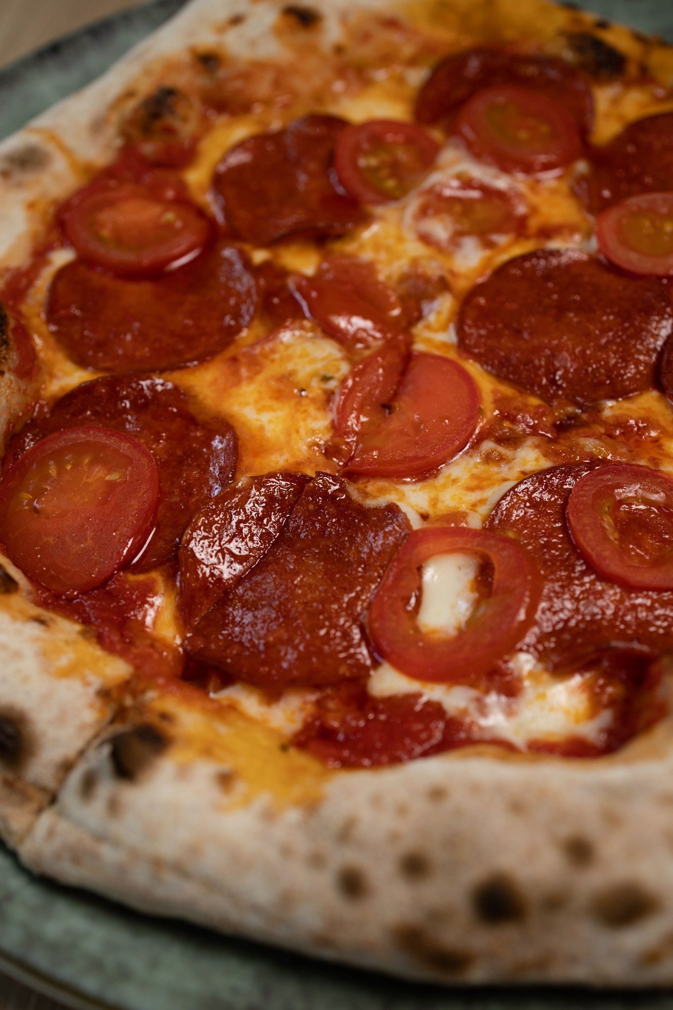 Frissen sült szalámis pizza koktélparadicsommal, közelről