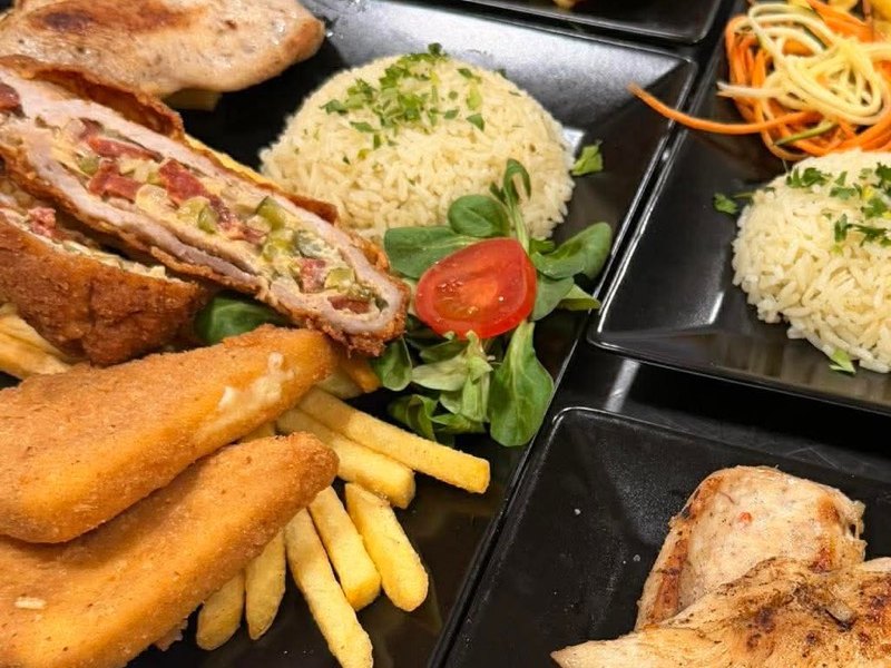 Sültes tál közelről: töltött hús, rántott sajt, grillezett csirke, rizs és hasábburgonya